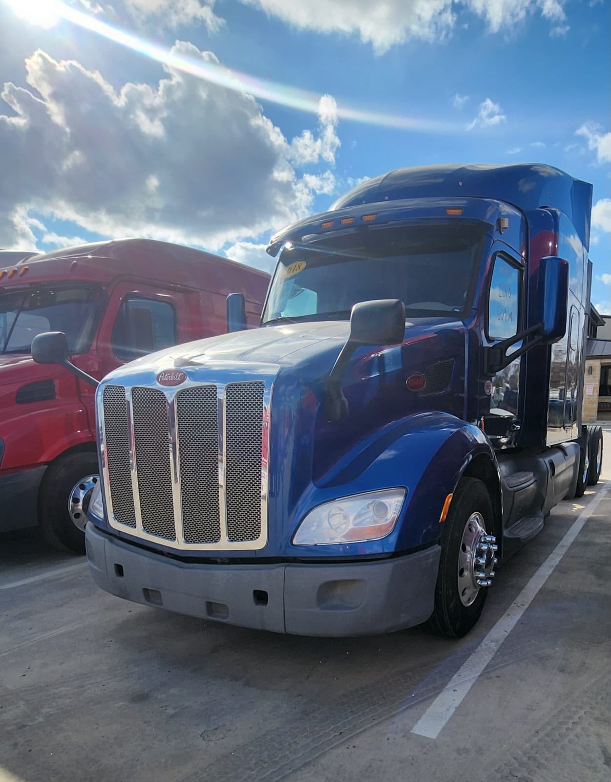 Blue Peterbilt sleeper truck parked beside other trucks