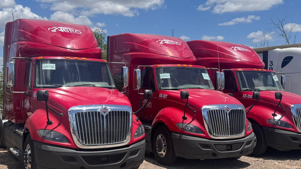 Fleet of red semi trucks lined up at a transport yard